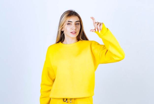 Retrato de mujer joven en traje amarillo posando y de pie