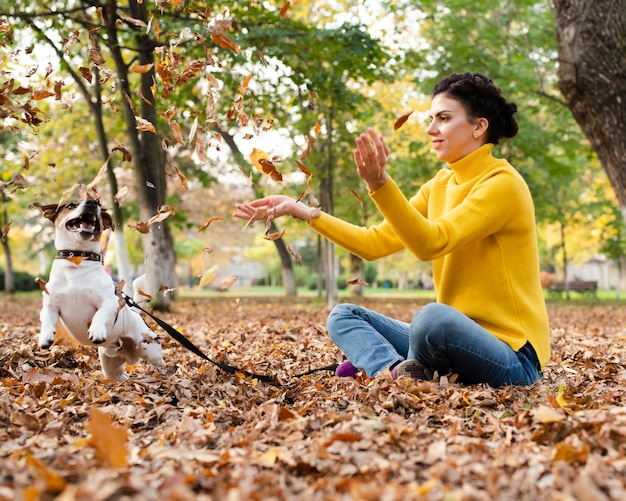 Retrato de mujer jugando con su perro en el parque