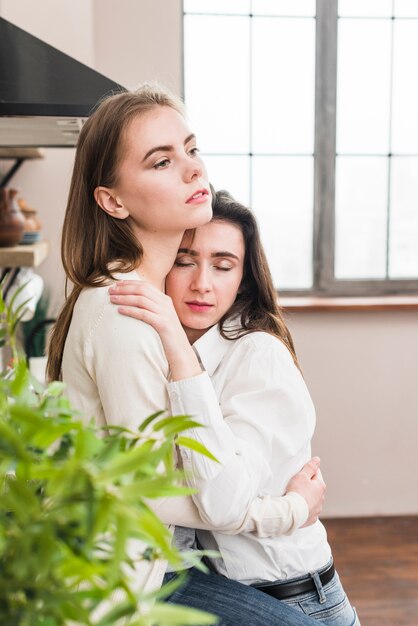 Retrato de mujer lesbiana abrazando a su novia mirando a otro lado