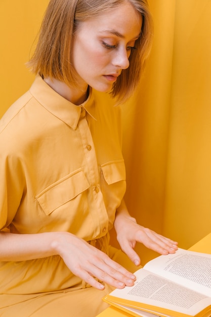 Retrato de mujer leyendo en un escenario amarilla