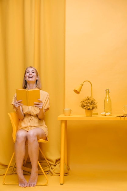 Foto gratuita retrato de mujer leyendo un libro en un escenario amarillo