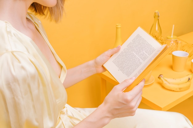Retrato de mujer leyendo un libro en un escenario amarillo
