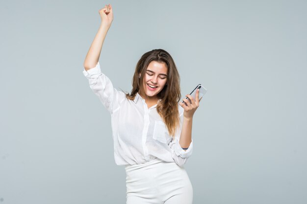 Retrato de una mujer linda alegre escuchando música en auriculares y bailando sobre un fondo blanco.