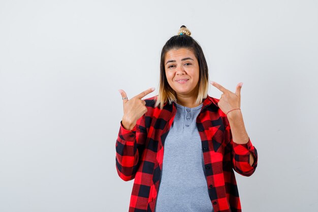 Retrato de mujer linda apuntando a su sonrisa en ropa casual y mirando alegre vista frontal