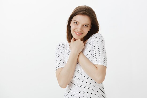 Retrato de mujer linda romántica y tierna presione las manos al pecho y sonriendo adorable