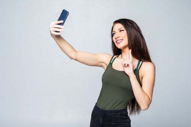 Retrato de mujer linda sonriente haciendo foto selfie en smartphone aislado