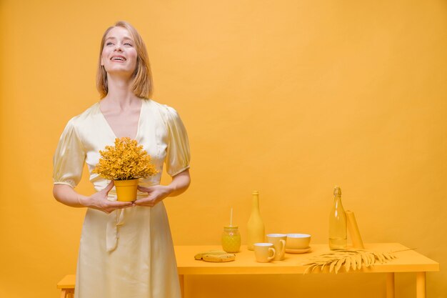 Retrato de mujer con una maceta en un escenario amarillo