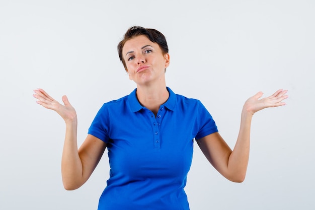 Retrato, de, mujer madura, actuación, indefenso, gesto, en, camiseta azul, y, mirar, vacilante, vista delantera