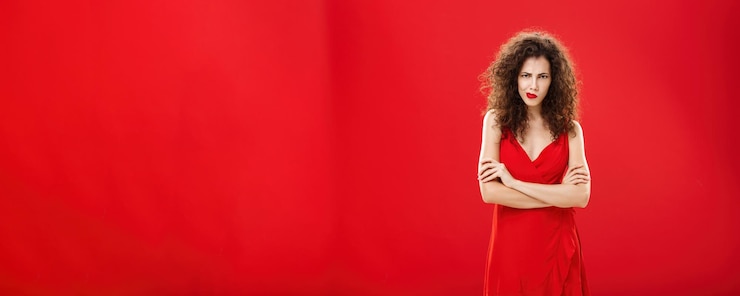 Foto gratuito retrato de una mujer de mal humor intensa y pensativa con peinado rizado frunciendo el ceño sonriendo mirando desde abajo
