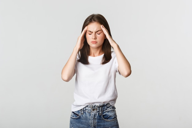 Retrato de mujer mareada o enferma tocando la cabeza y haciendo muecas de dolor, dolor de cabeza, migraña.