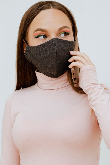 Retrato de mujer con máscara hablando por teléfono inteligente