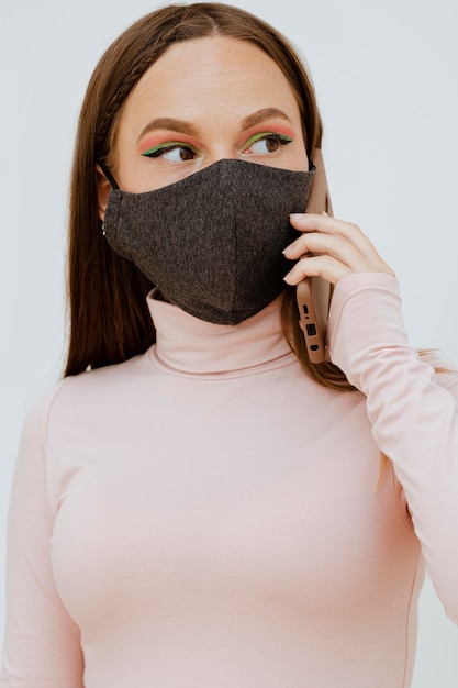 Retrato de mujer con máscara hablando por teléfono inteligente