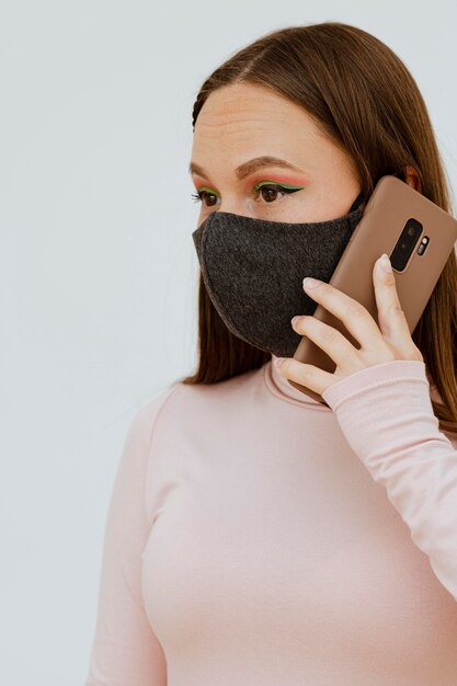 Retrato de mujer con máscara médica hablando por teléfono inteligente