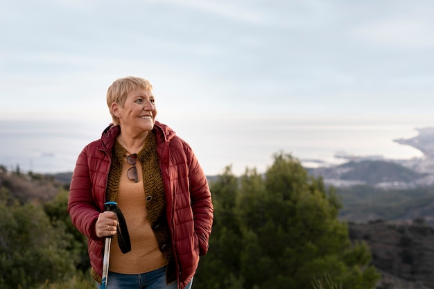 Retrato de mujer mayor en una aventura en la naturaleza con bastón de trekking