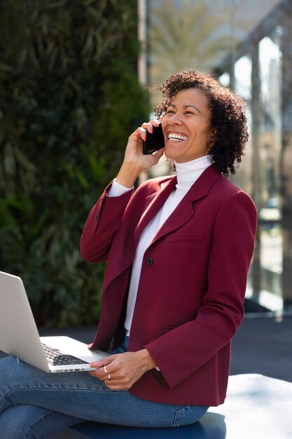 Retrato de mujer mayor en blazer profesional al aire libre y teléfono inteligente