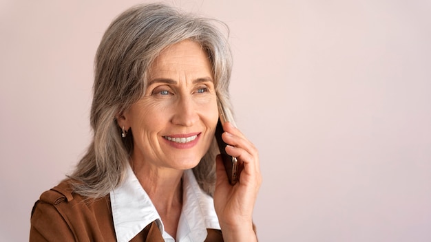 Retrato de mujer mayor sonriente tomando el teléfono