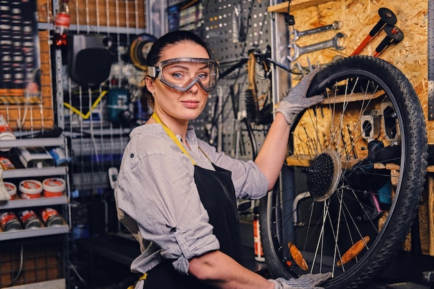 Retrato de mujer mecánica de bicicletas sobre fondo de soporte de herramientas.