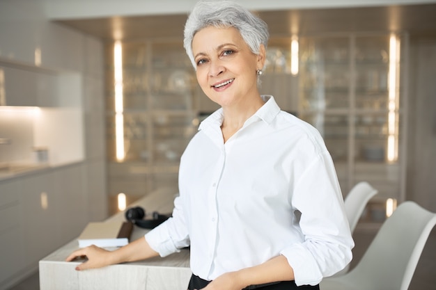 Foto gratuita retrato de mujer de mediana edad gerente de eventos con elegante corte de pelo trabajando en su oficina