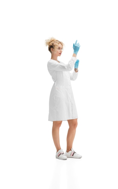 Foto gratuita retrato de mujer médico, enfermera o cosmetóloga en uniforme blanco y guantes azules sobre blanco