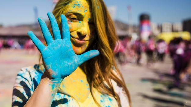 Retrato de una mujer mirando la cámara que muestra la mano pintada de azul