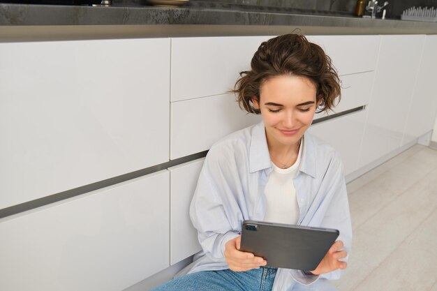 Retrato de mujer mirando su tableta leyendo en línea viendo videos en un dispositivo digital sentado en