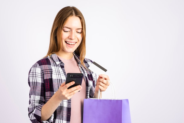 Retrato mujer mirando el teléfono y sosteniendo una bolsa