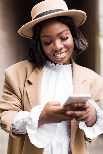 Foto gratuita retrato de mujer de moda sonriente mirando su teléfono