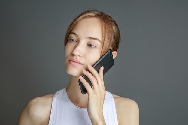 Retrato de una mujer morena de 20 años usando un teléfono celular mientras estaba aislada sobre un fondo amarillo