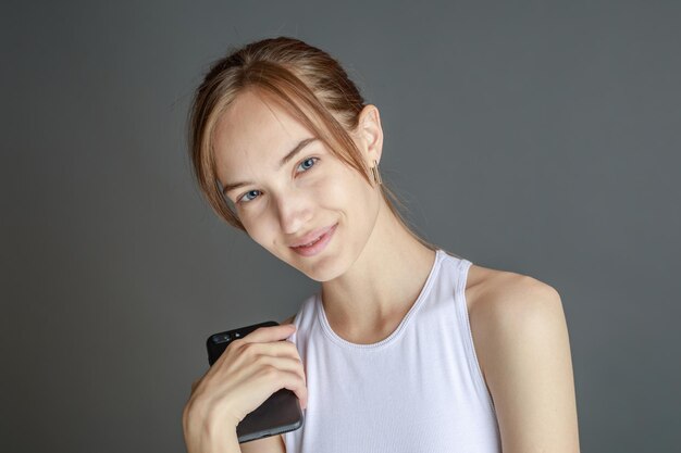 Retrato de una mujer morena de 20 años usando un teléfono celular mientras estaba aislada sobre un fondo amarillo