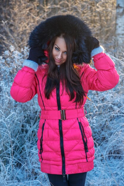 Retrato de mujer morena en abrigo de invierno rosa.