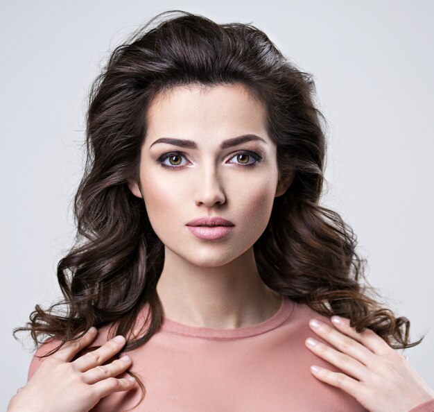 Retrato de mujer morena con hermoso cabello largo y castaño. Chica adulta bastante joven posando en el estudio. Primer rostro femenino atractivo.