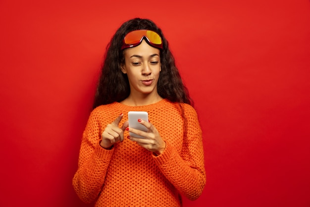 Retrato de mujer morena joven afroamericana en pasamontañas en espacio rojo