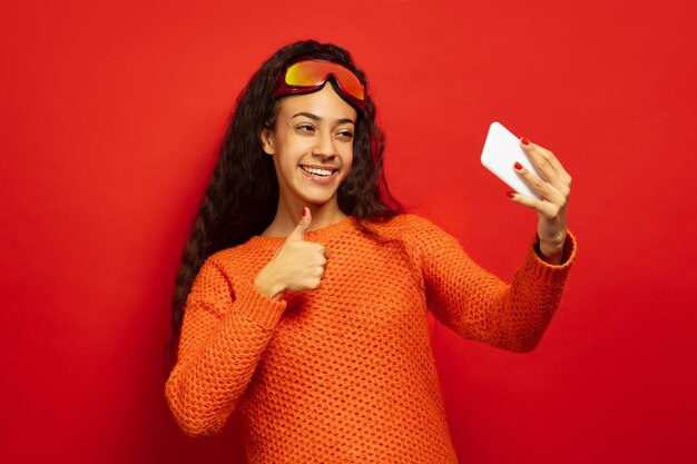 Retrato de mujer morena joven afroamericana en pasamontañas en espacio rojo