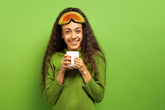 Retrato de mujer morena joven afroamericana en pasamontañas en verde