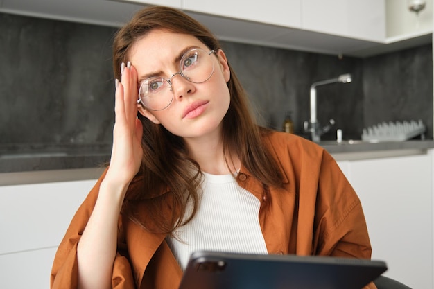 Foto gratuita retrato de una mujer morena que trabaja desde casa con gafas mirando preocupada tocando la cabeza y