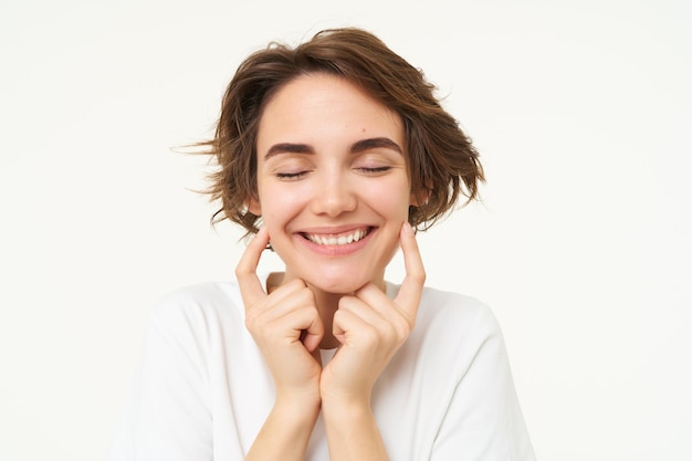 Foto gratuita el retrato de una mujer morena sonriendo cierra los ojos y toca los hoyuelos en sus mejillas.