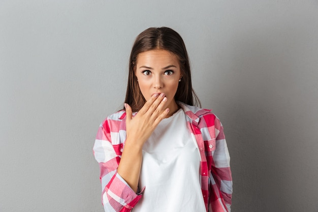 Retrato de una mujer morena sorprendida en camisa a cuadros