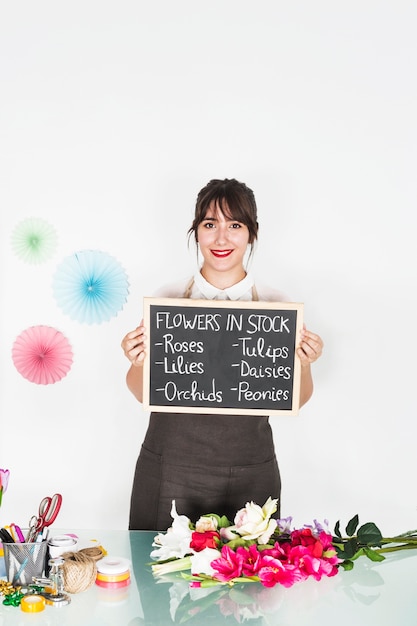 Foto gratuita retrato de una mujer mostrando flores en stock en pizarra