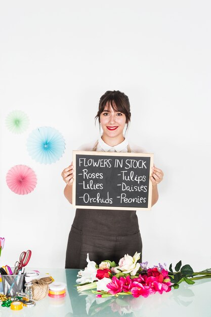 Retrato de una mujer mostrando flores en stock en pizarra