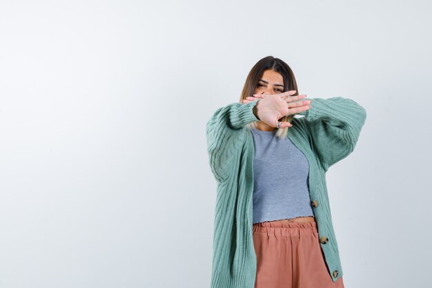 Retrato de mujer mostrando gesto de parada en ropa casual y mirando confiada vista frontal