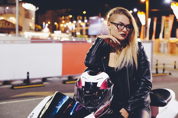 Retrato mujer motorista disfrutando la vida nocturna de la ciudad sentado en moto