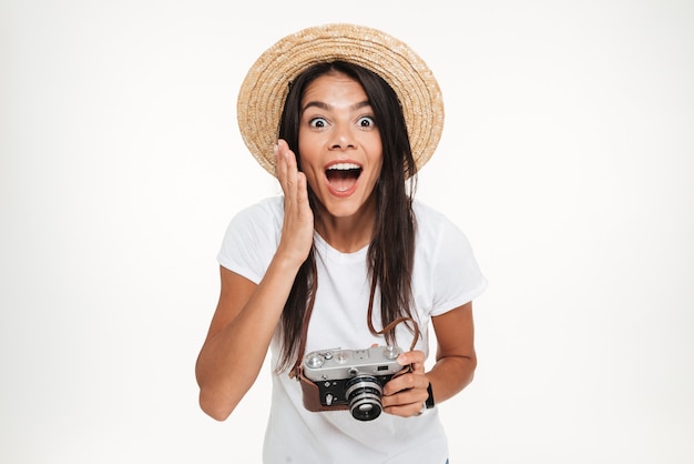Retrato de mujer muy emocionada con sombrero sosteniendo una cámara