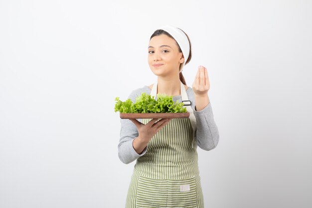 Retrato de una mujer muy linda sosteniendo una tabla de madera con lechuga fresca