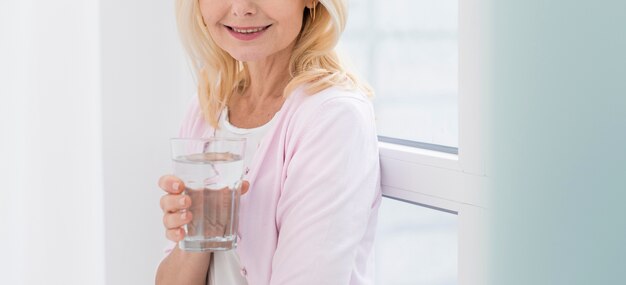 Retrato de mujer muy madura sosteniendo un vaso de agua