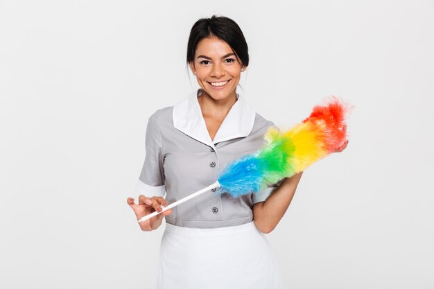 Retrato de mujer muy sonriente en uniforme con colorido limpiador de polvo