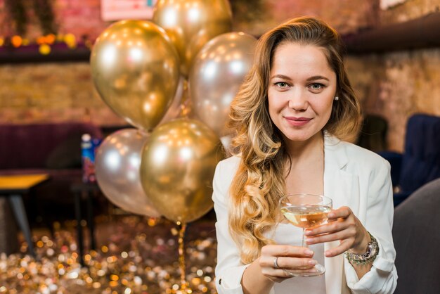 Retrato de una mujer muy sonriente con vaso de whisky en fiesta