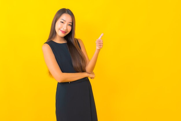 Retrato de mujer de negocios asiática joven hermosa sonrisa con acción sobre fondo de color amarillo