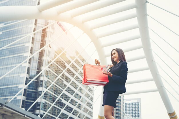 Retrato de mujer de negocios con compras de bolsa roja al aire libre.