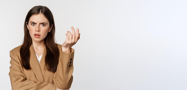 Foto gratuita retrato de una mujer de negocios confundida que mira desconcertada y frustrada no puede entender algo de pie en traje sobre fondo blanco