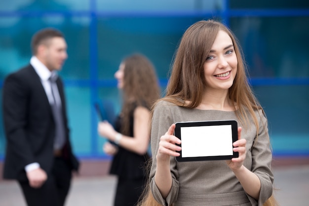 Foto gratuita retrato de mujer de negocios feliz joven mostrando la pantalla de la tableta de espacio de copia